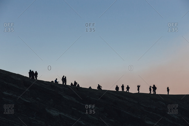 Travelers silhouetted on a ridgeline as they climb Mount Bromo