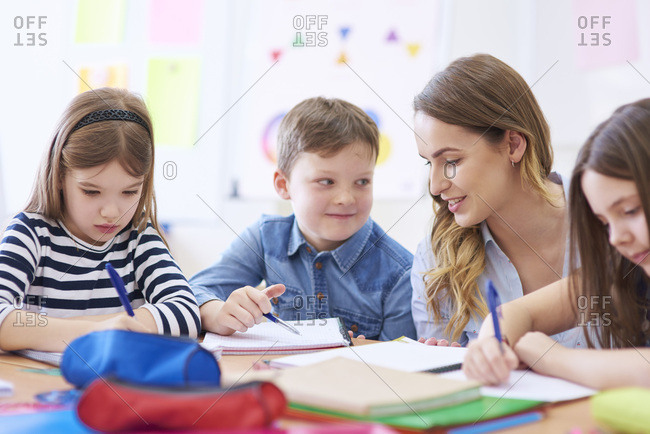 Teacher helping pupils with their tasks in class