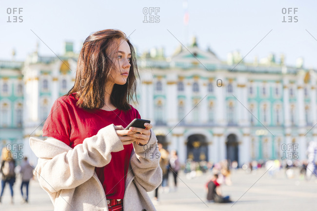 Russia- St. Petersburg- young woman using smartphone in the city