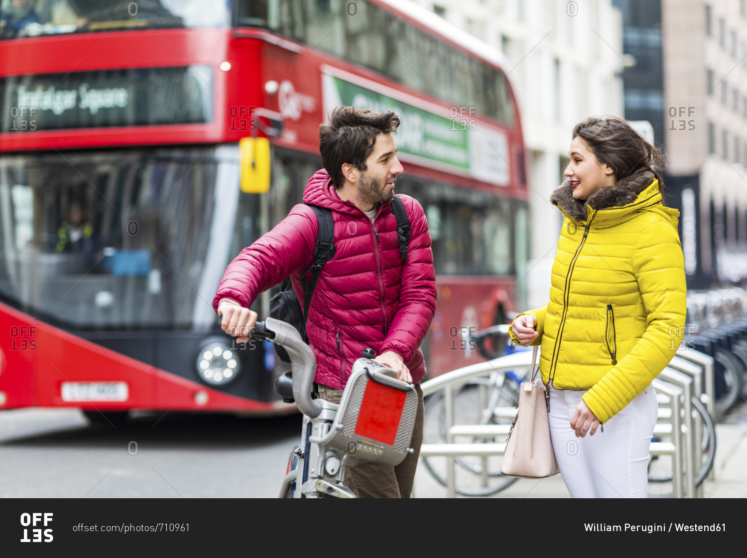UK- London- young man with rental bicycle from bike share stand  talking to his girlfriend