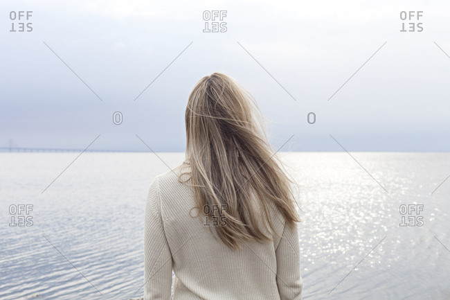 Blonde Woman Staring At Ocean From Behind Stock Photo Offset