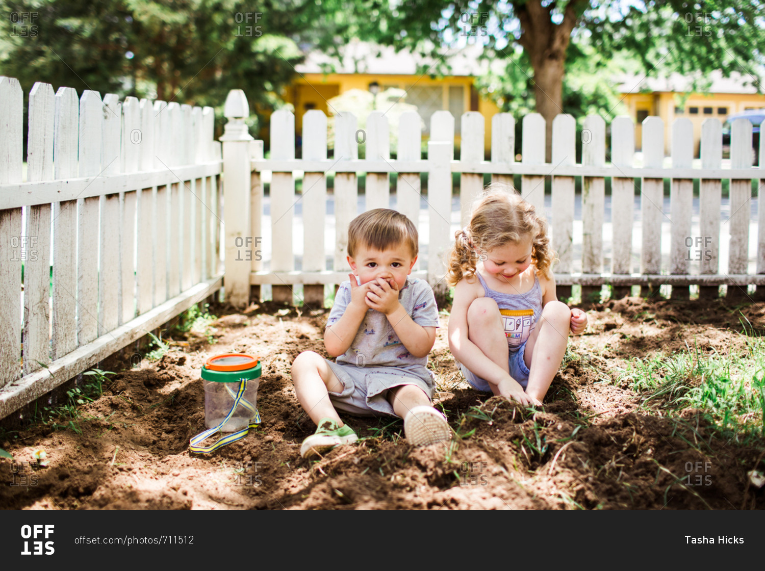 Two kids looking for bugs in the dirt