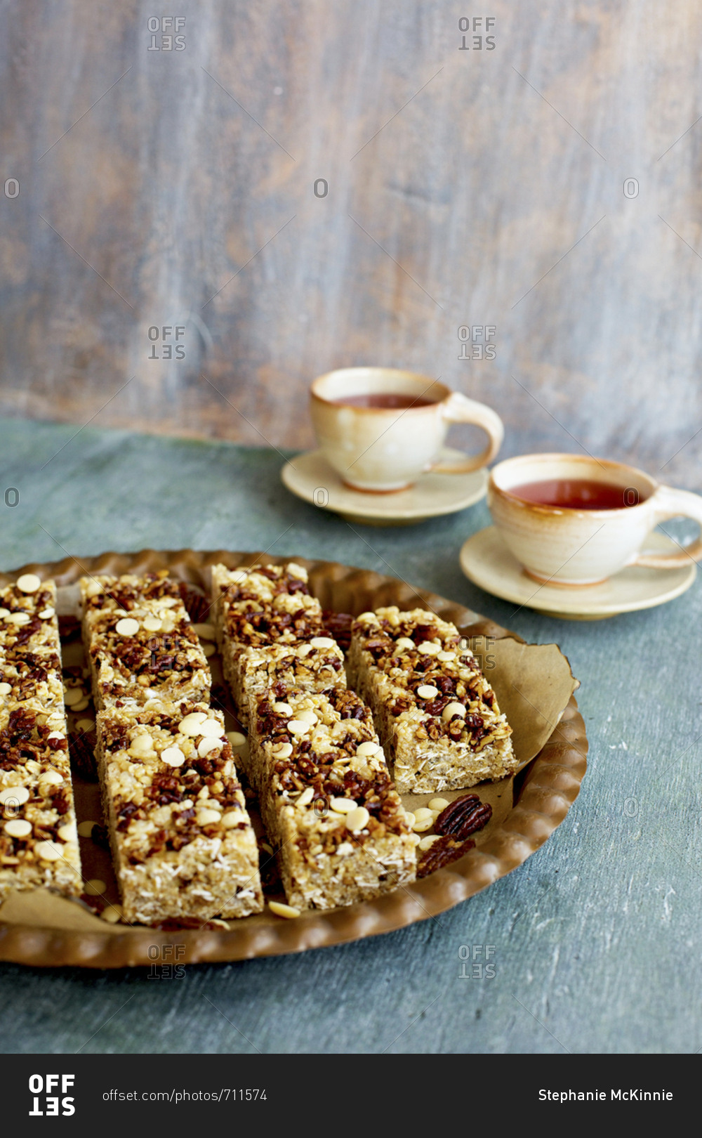 Pecan white chocolate breakfast bars on plate served with cups of hot tea