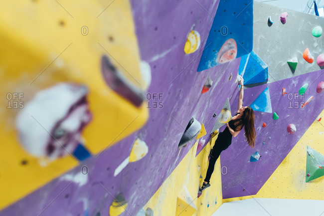 Young woman climbing rock wall indoor