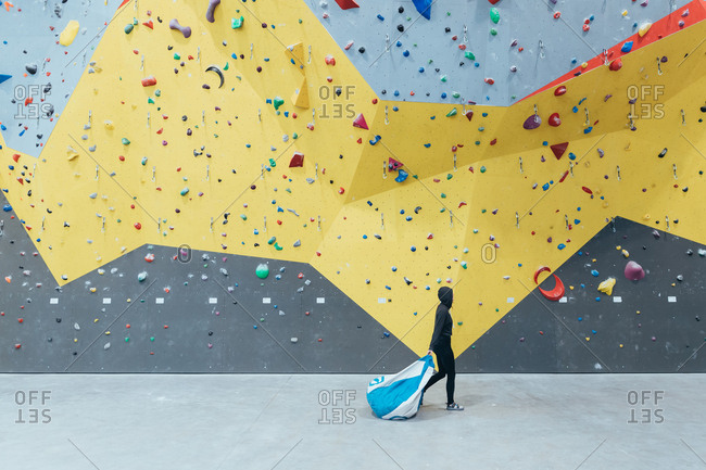 Young woman walking in front of climbing rock wall indoor