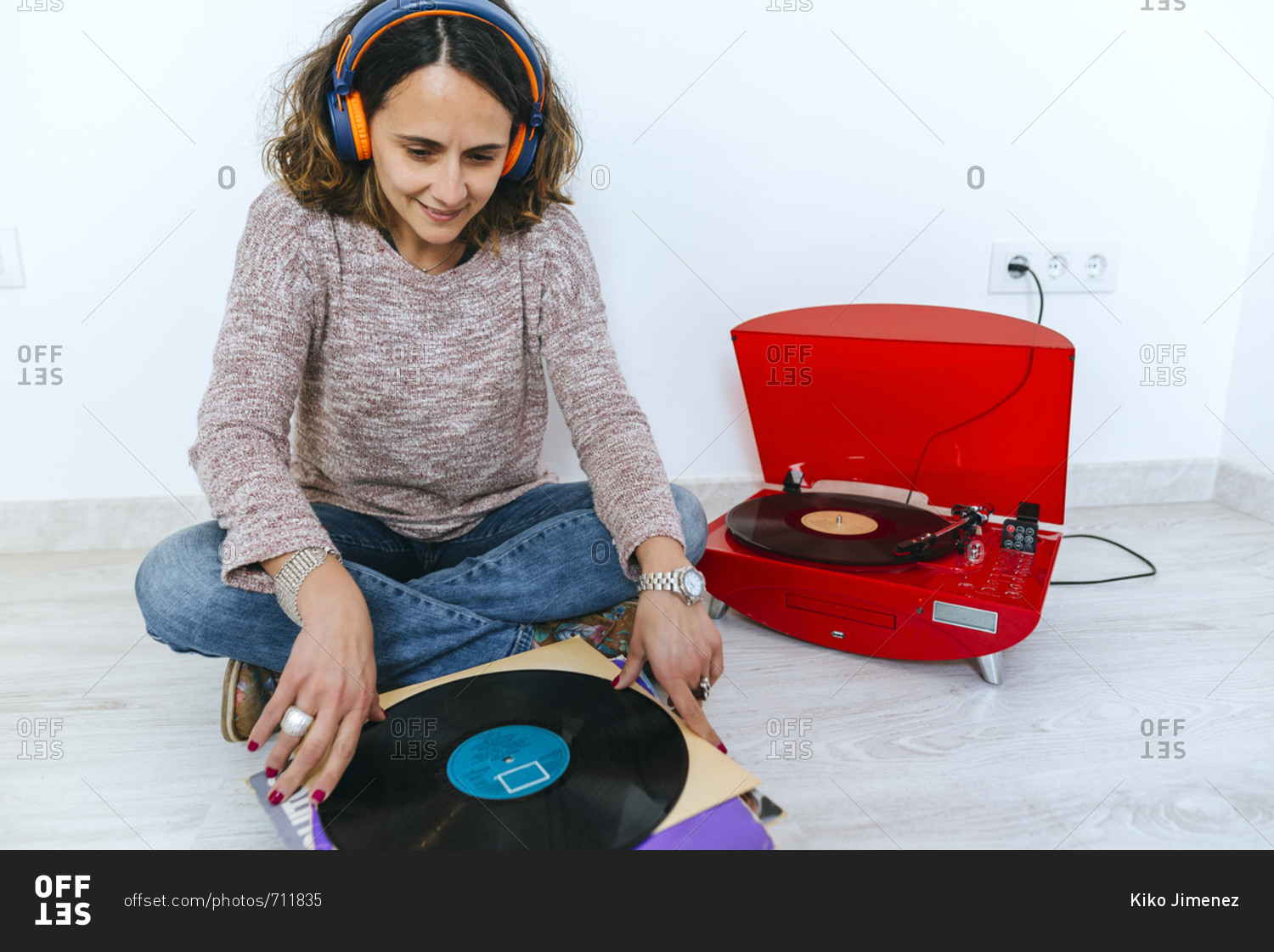 Woman looking at pile of vinyl records as she listens to retro looking record player