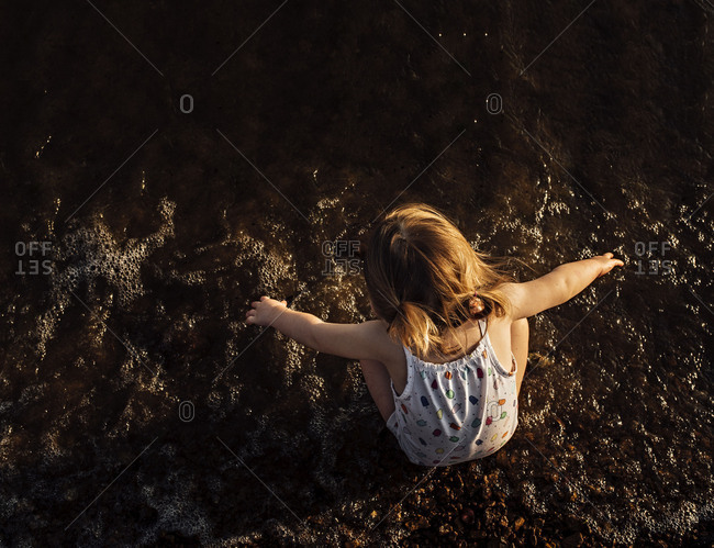Overhead view of young girl sitting in lake enjoying the water