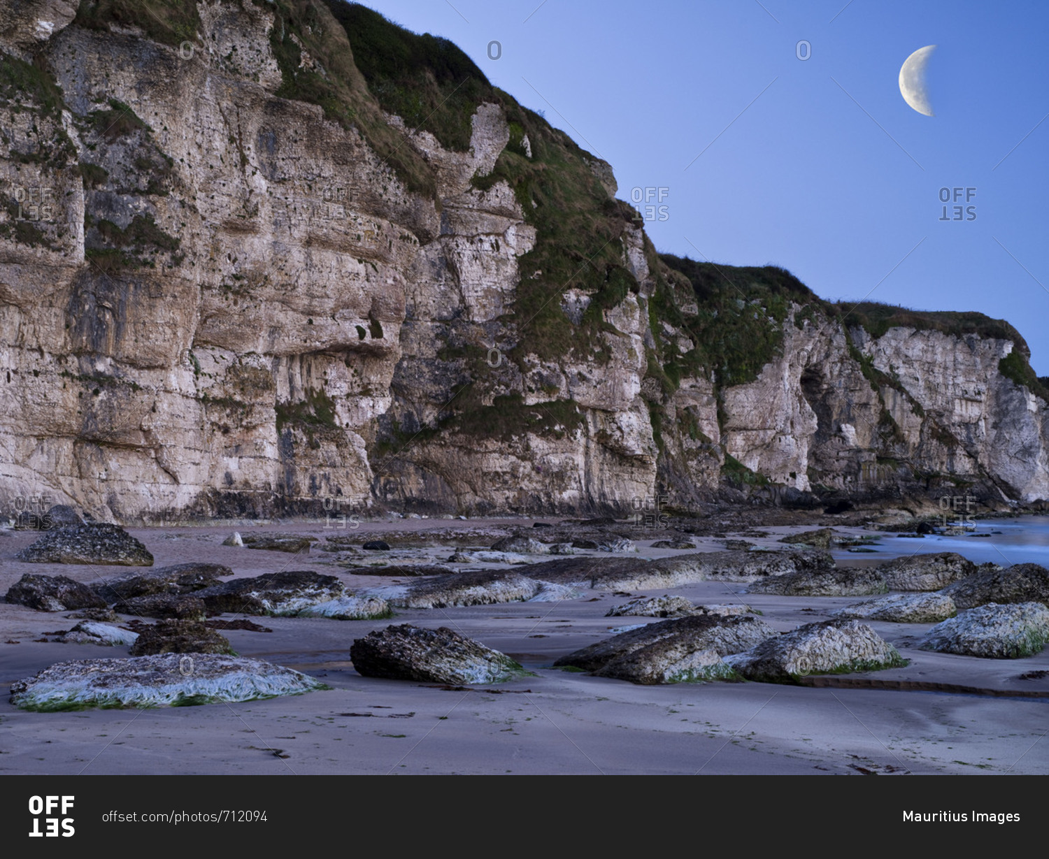 Northern Ireland, Antrim, Causeway Coast, steep coast made of mussel limestone close Ballintoy, blue hour, evening sky with moon
