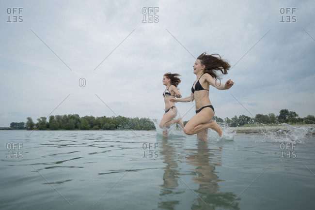 Two girls while bathing in the lake, quarry pond Liedolsheim, Dettenheim, Baden-Wurttemberg, Germany