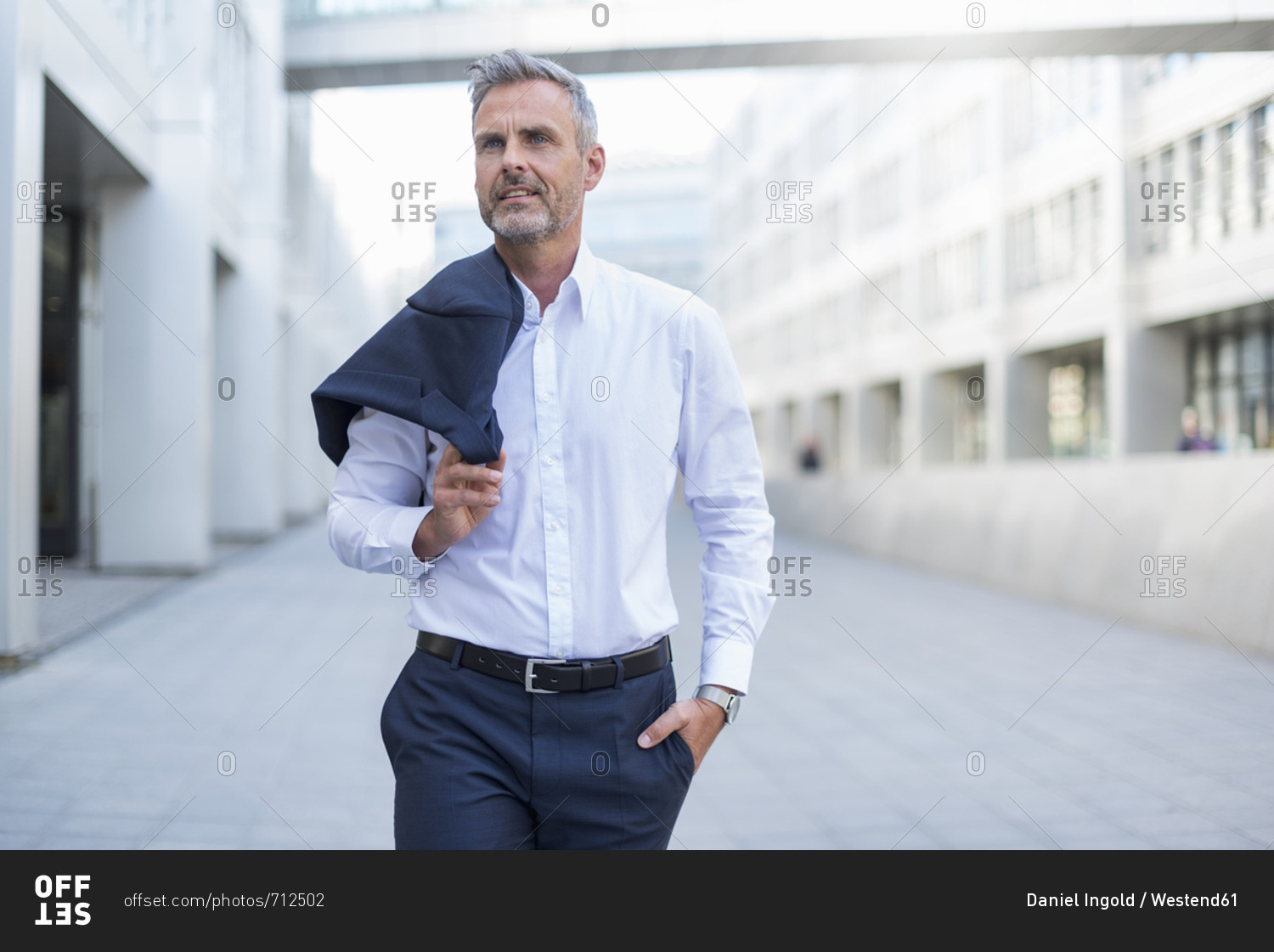 Portrait of businessman walking at courtyard of modern office building