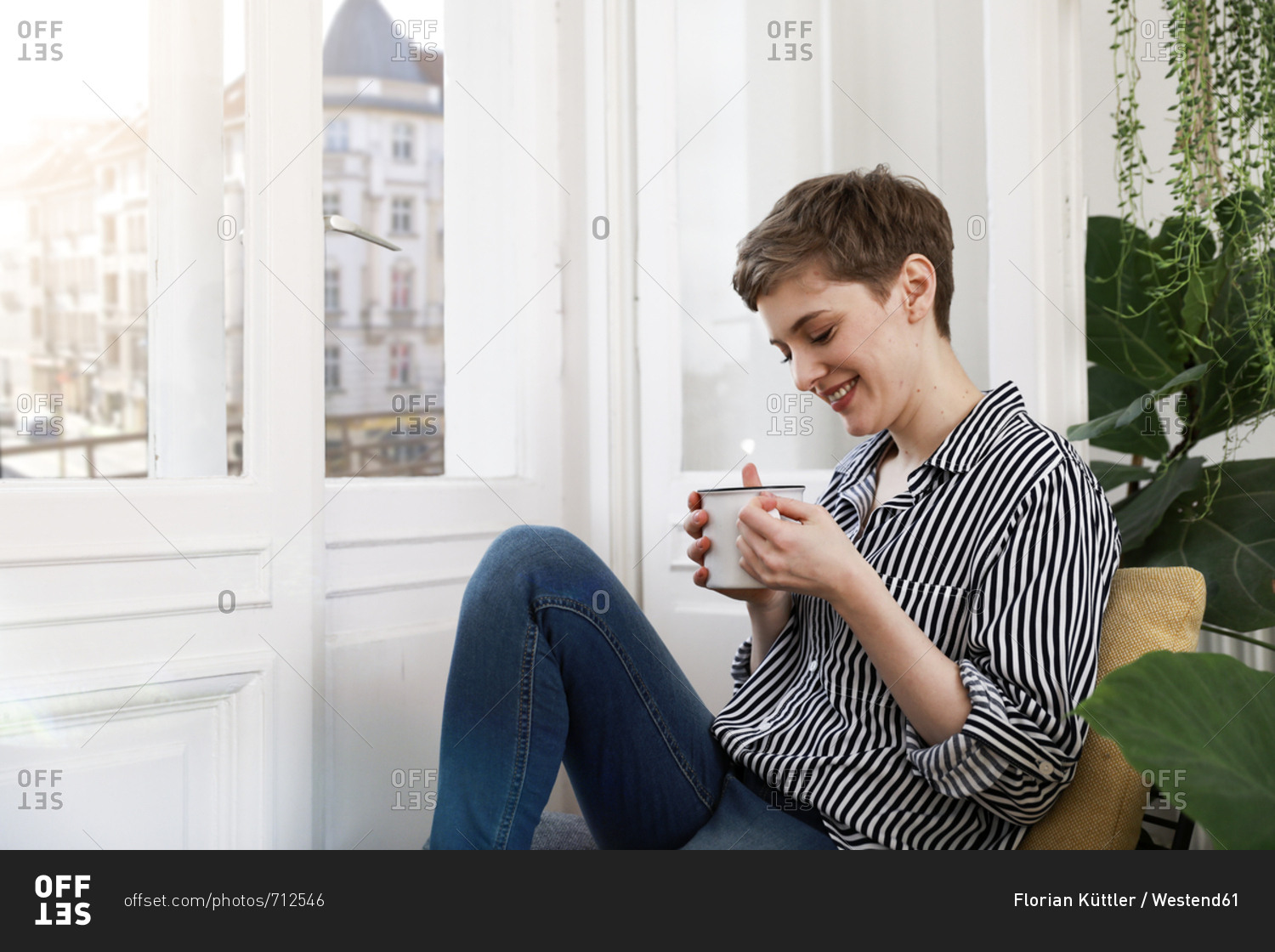 Happy woman sitting relaxed at window- drinking coffee