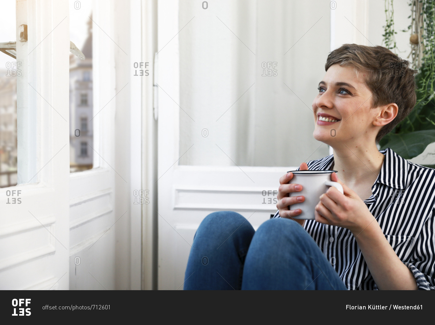 Happy woman sitting relaxed at window- drinking coffee