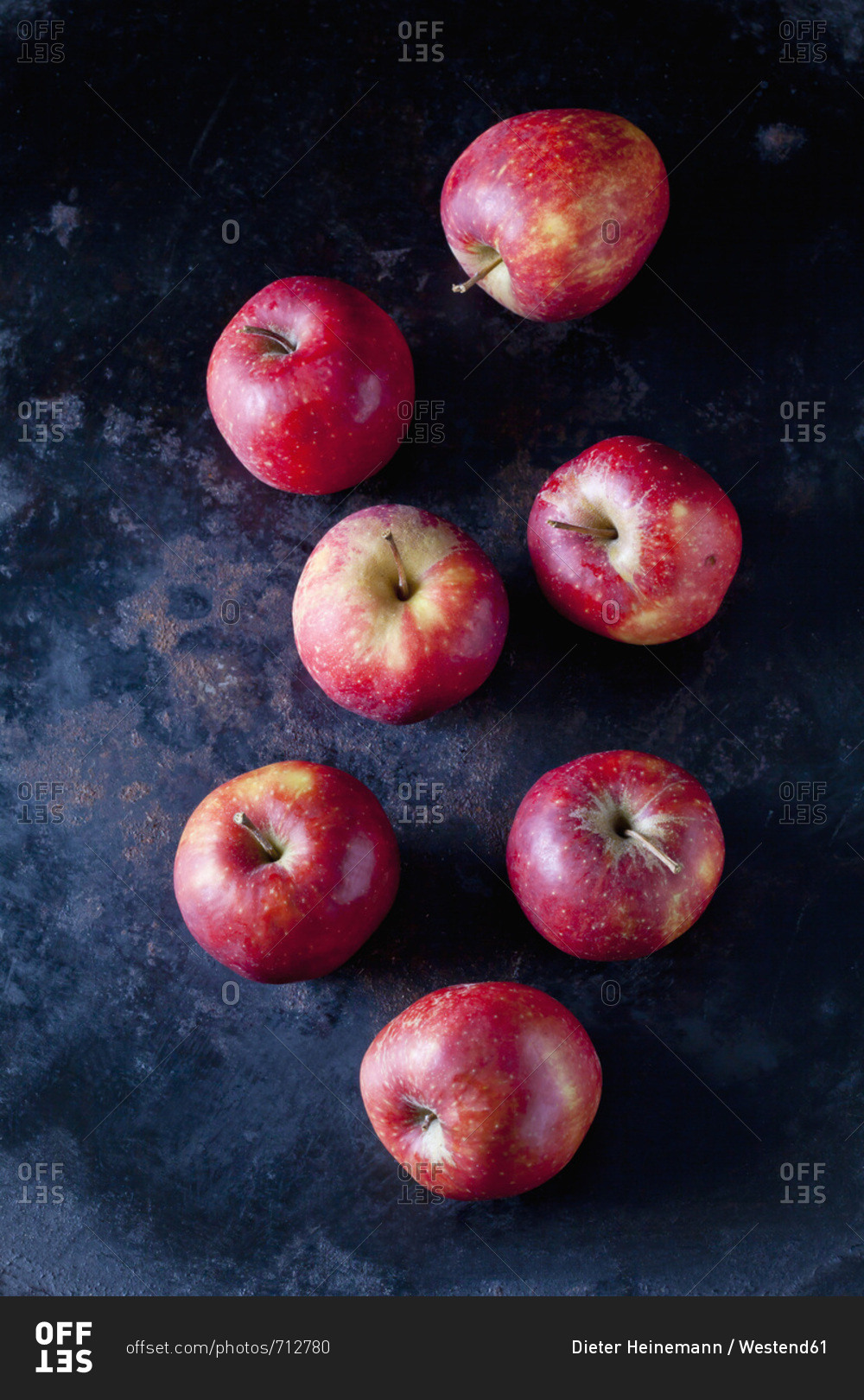 Seven red apples on dark ground