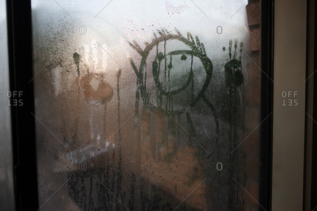 Faces and hand prints in condensation on window