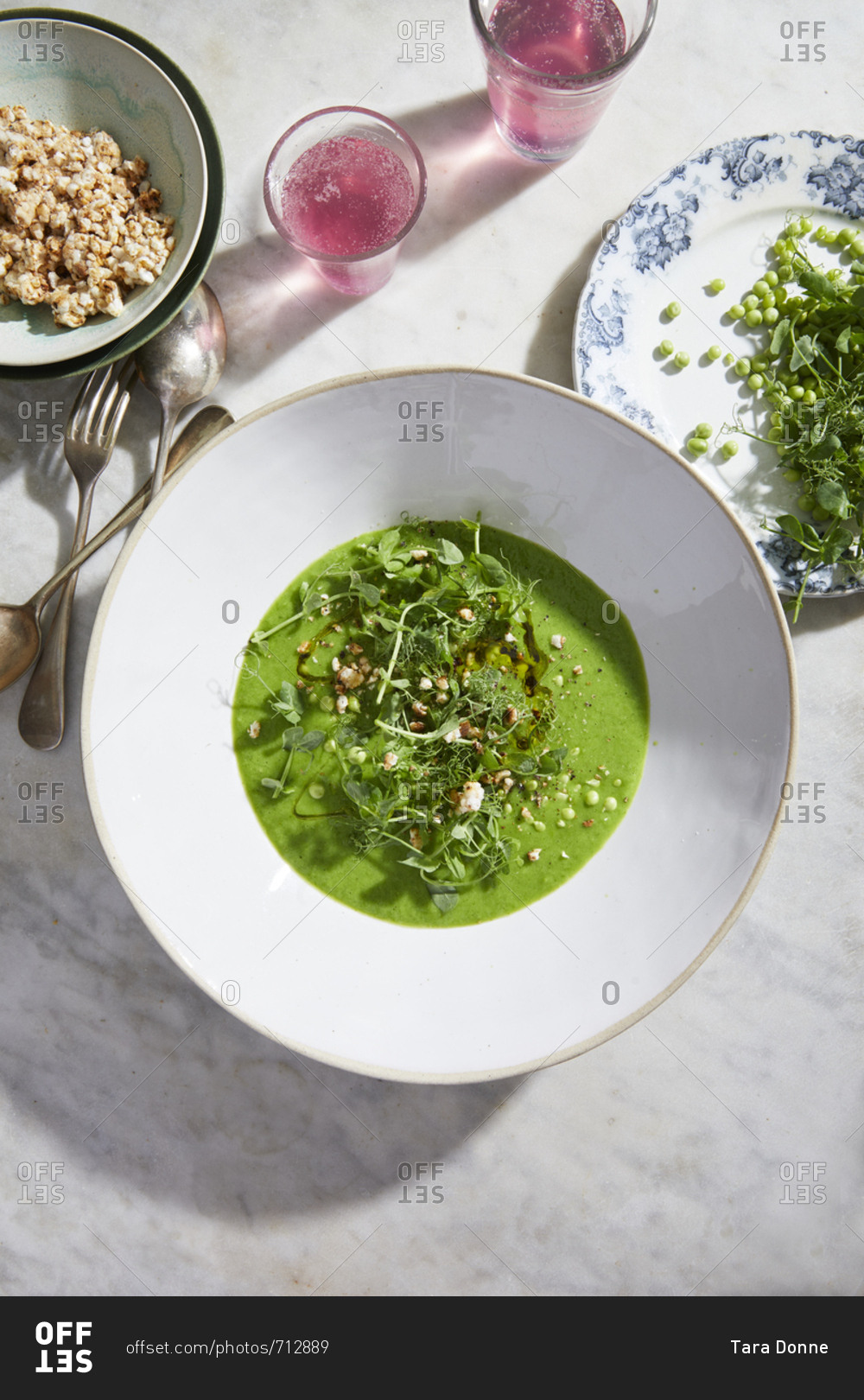 Pea soup and salad bowl with pea tendrils, toasted rice cake, and sparkling rose