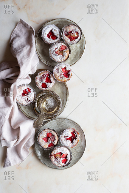 Overhead view of gluten free strawberry muffins on plates and sprinkled with confectioners sugar