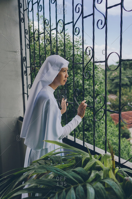 PHILIPPINES, APRIL 16, 2018: cheerful nun in white gowns looking through the fence