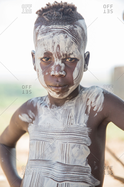 Ethiopia - November, 25, 2014: Crop view of african kid smeared in white clay standing and looking at camera