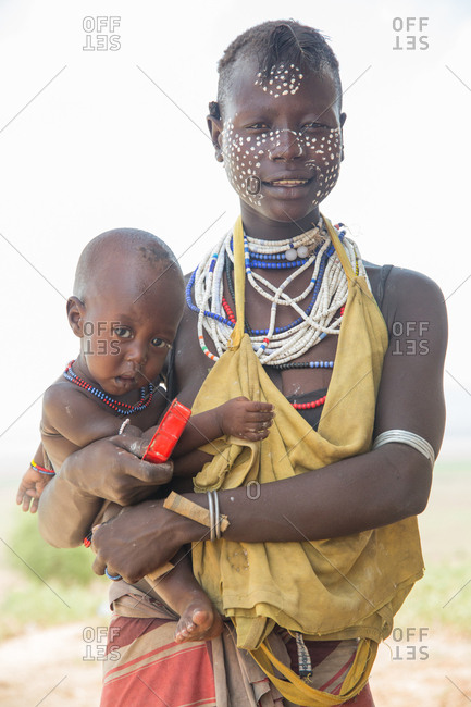 Ethiopia - November, 25, 2014: Crop view of african frowning female in military clothes holding baby waving arms and looking at camera