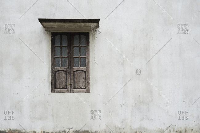 Minimal shot of classic window built in wood against grey wall.