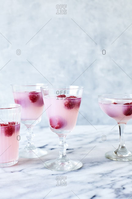 Pink lemonade jelly with raspberries on light marble background