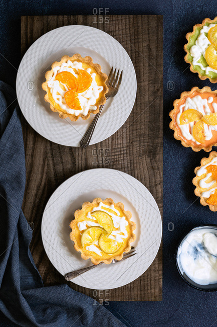Lemon tarts on plates alongside a bowl of yoghurt and a lime and orange tart.
