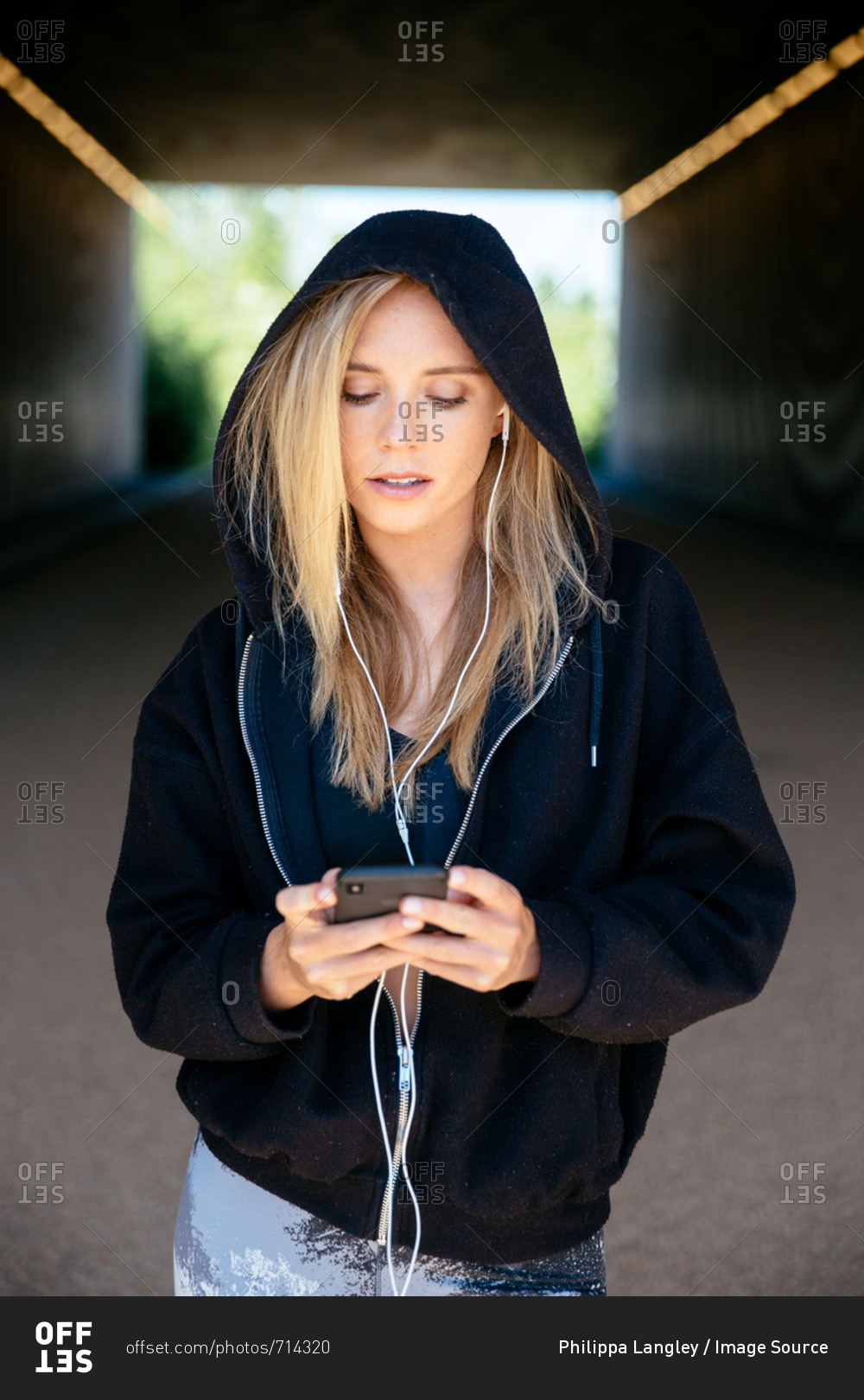 Young woman listening to music on mobile phone in tunnel