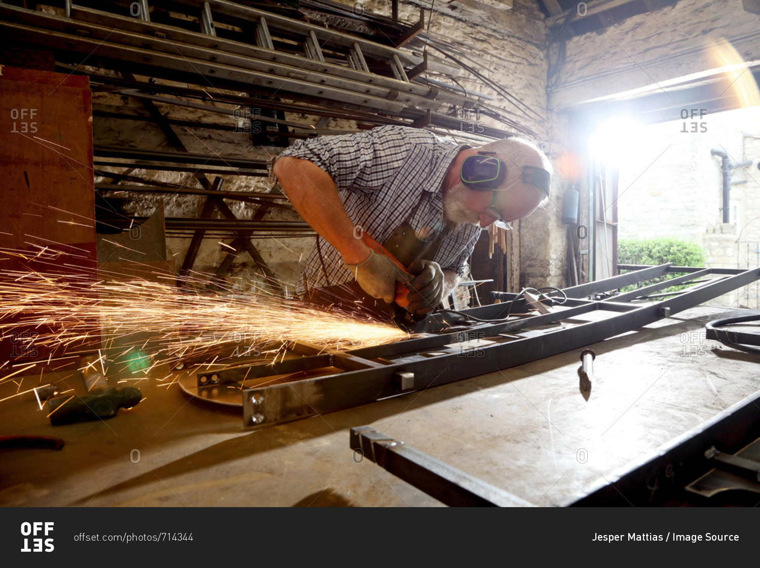 Blacksmith grinding metal on workbench in blacksmiths shop