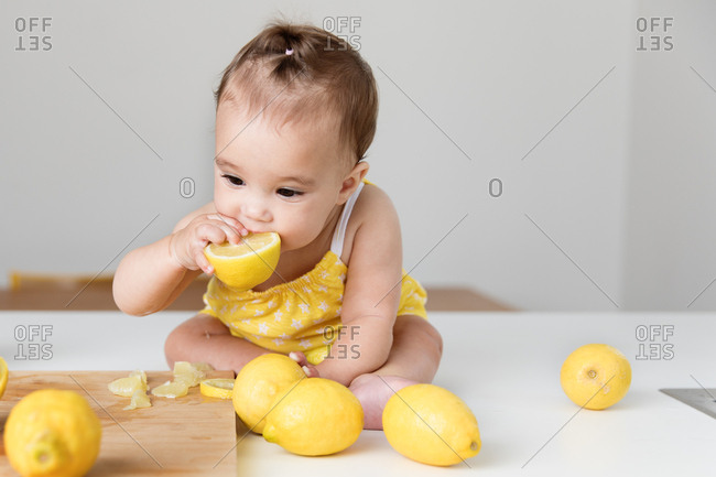 Baby girl chewing on a lemon