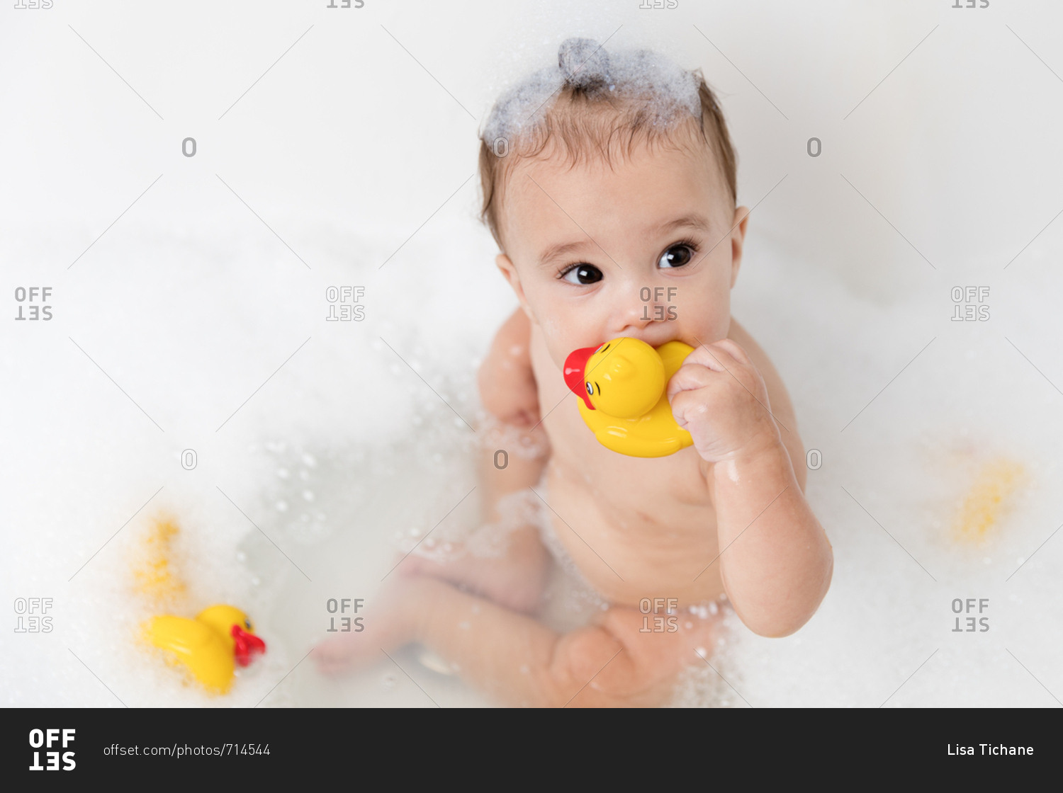 Little baby in bubble bath with rubber ducks