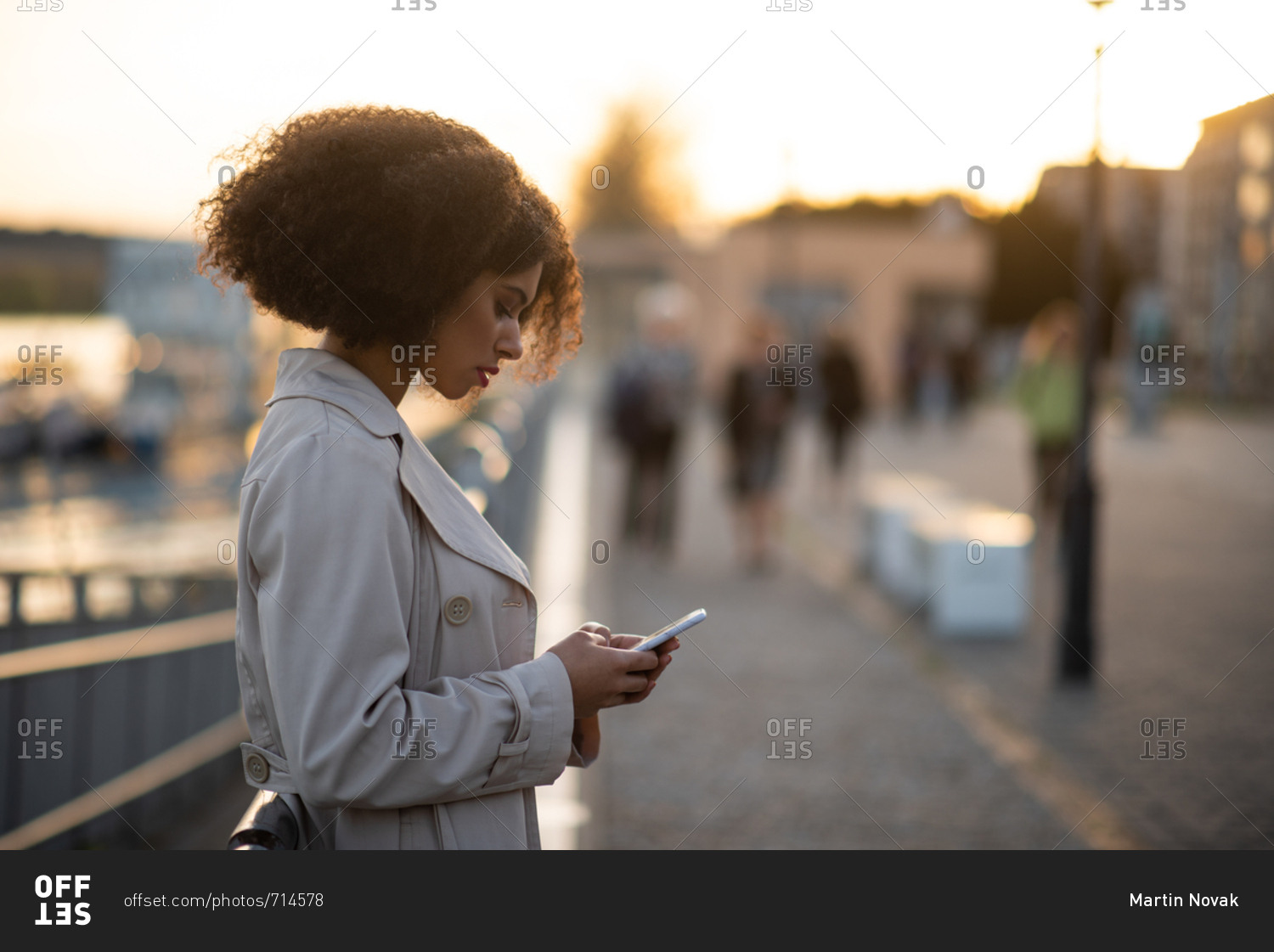 Sad young African-American teen looking at her phone in street