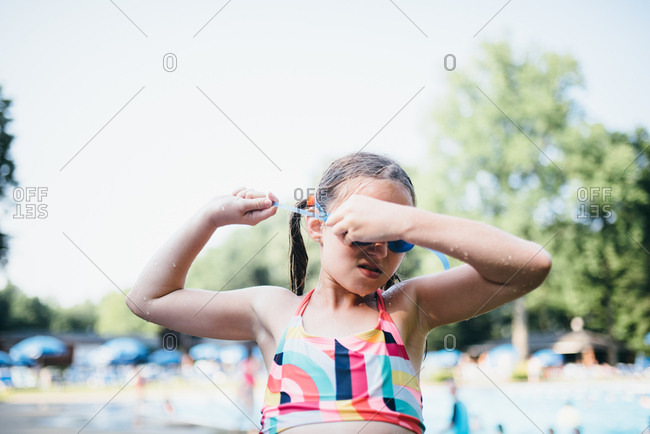 Wet girl in bathing suit pulling off goggles after swim