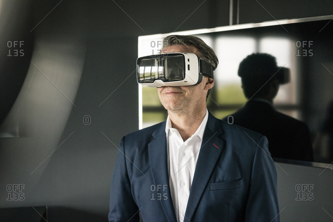 Mature businessman wearing VR glasses in office