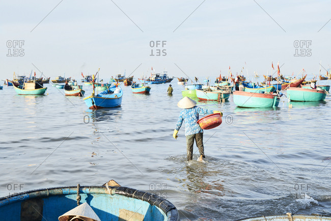 Vietnamese woman carrying seafood at seashore for sell with wholesale buyer at clandestine fishing market
