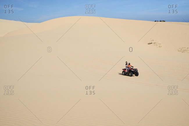 Mui Ne, Vietnam - January 6, 2018: Full length view of group of tourists driving red squad at the white sand dunes in Mui Ne
