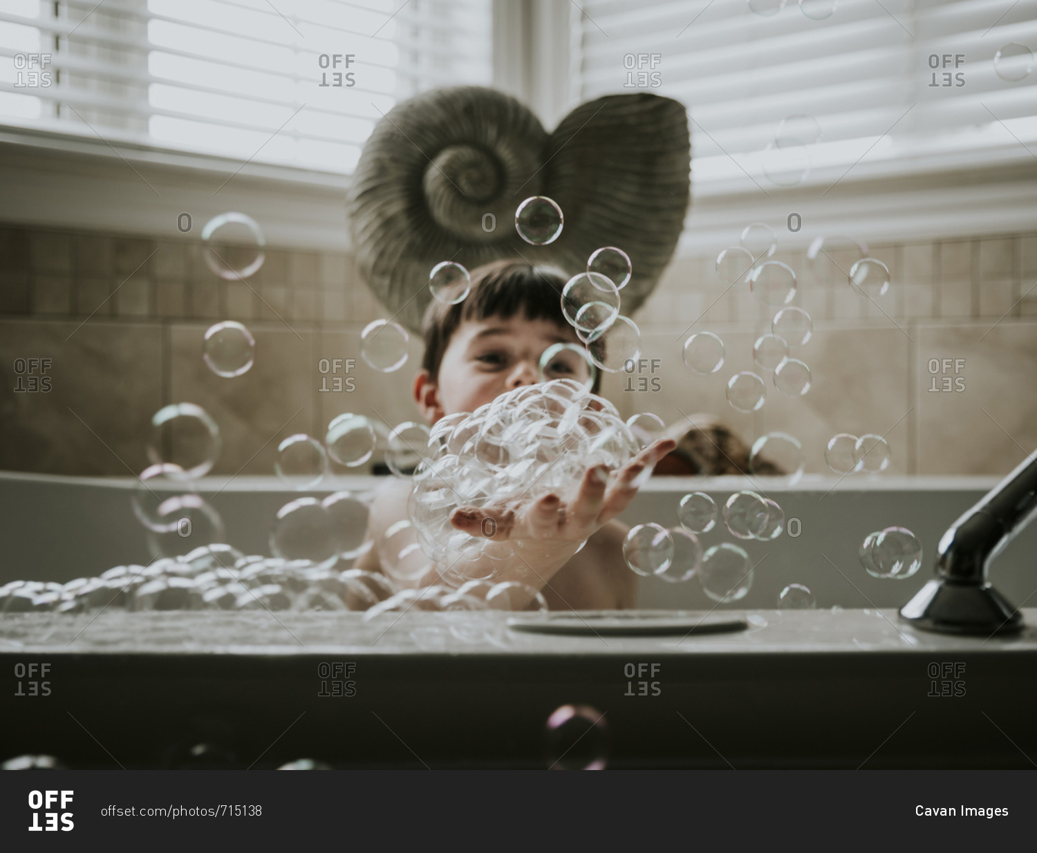 Boy playing with bubbles while taking bath in bathtub stock photo OFFSET