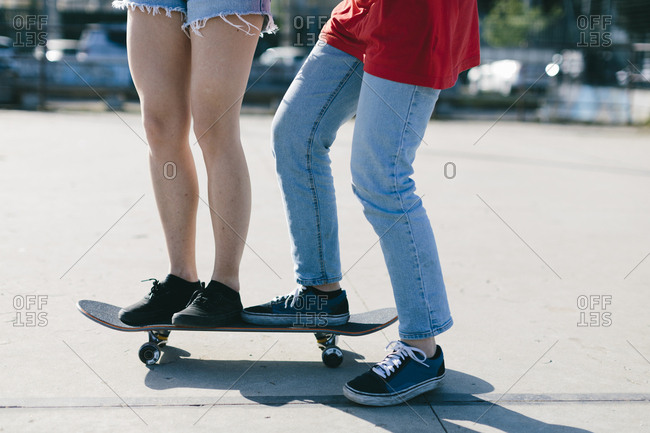 Low section of lesbian couple skateboarding on street