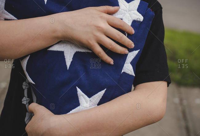 Midsection of boy holding American flag while standing at yard