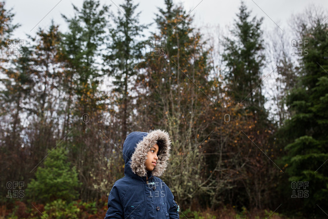 Young girl wearing blue jacket with furry hood in the woods