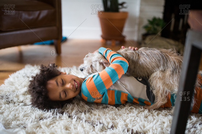 Young girl cuddling on floor with furry dog