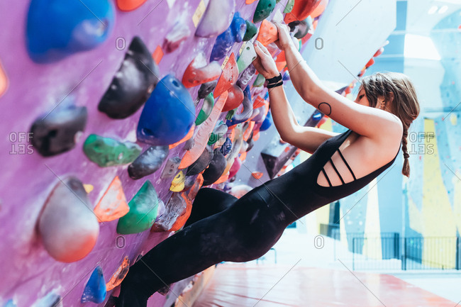 Young woman climbing an indoor rock wall