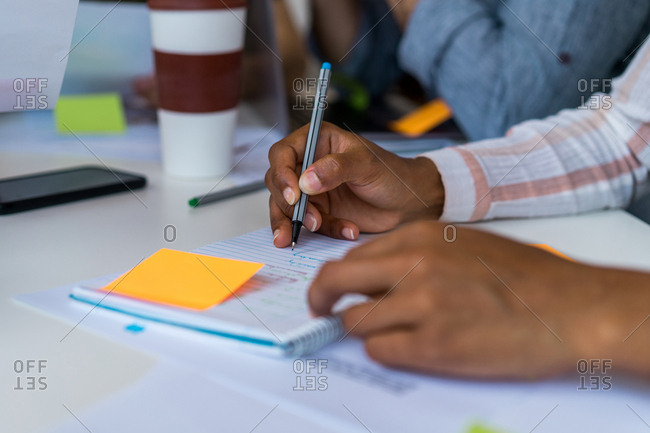 Crop hands marking items on scheme