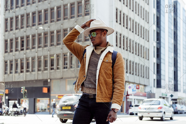 Young african male in hat and glasses walking on the street