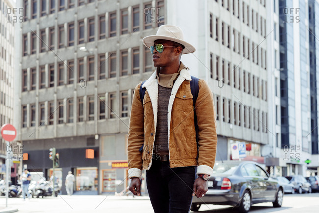 Young african male in hat and glasses walking on the street