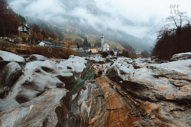 View to wet rocks and small mountain town in foggy day.
