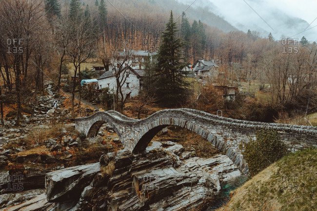 Small stone-made wavy bridge in the village in autumn.