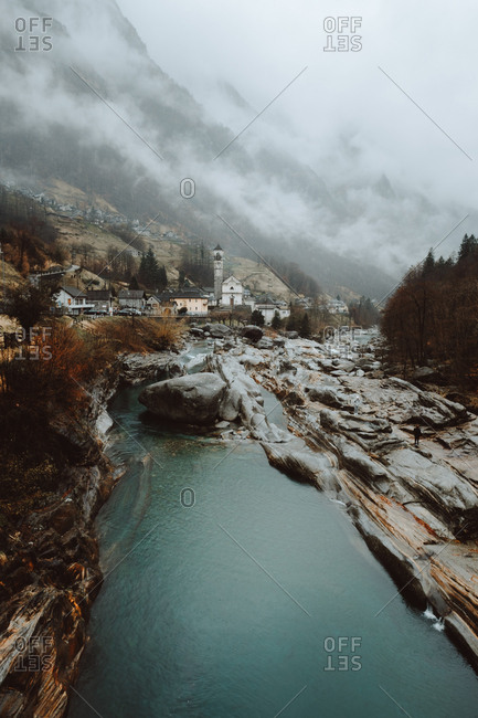 View to small blue river flowing and small town in the mountains.