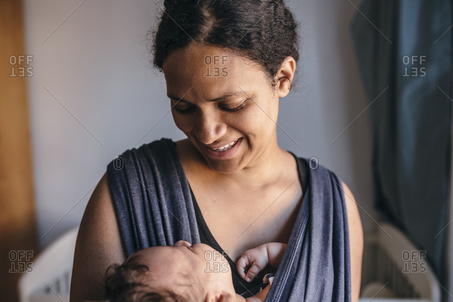 Mother smiles at his baby boy in sling