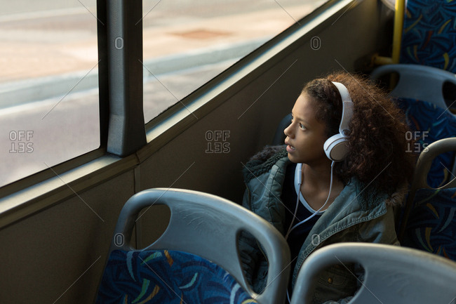 Teenage girl listening music on headphones while travelling in the bus