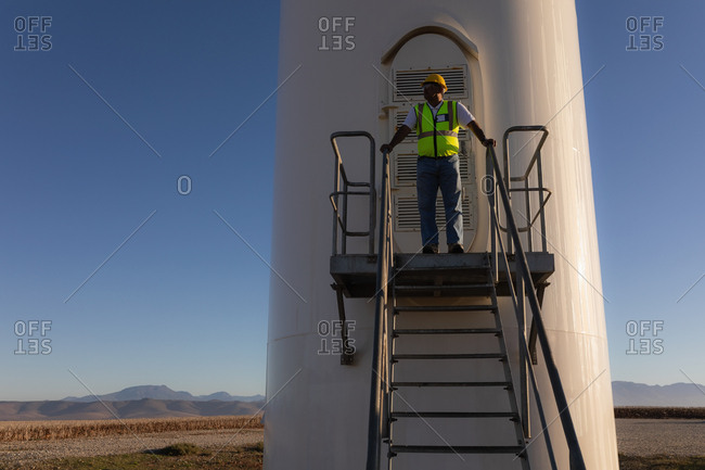 Engineer standing at entrance of a wind mill at a wind farm